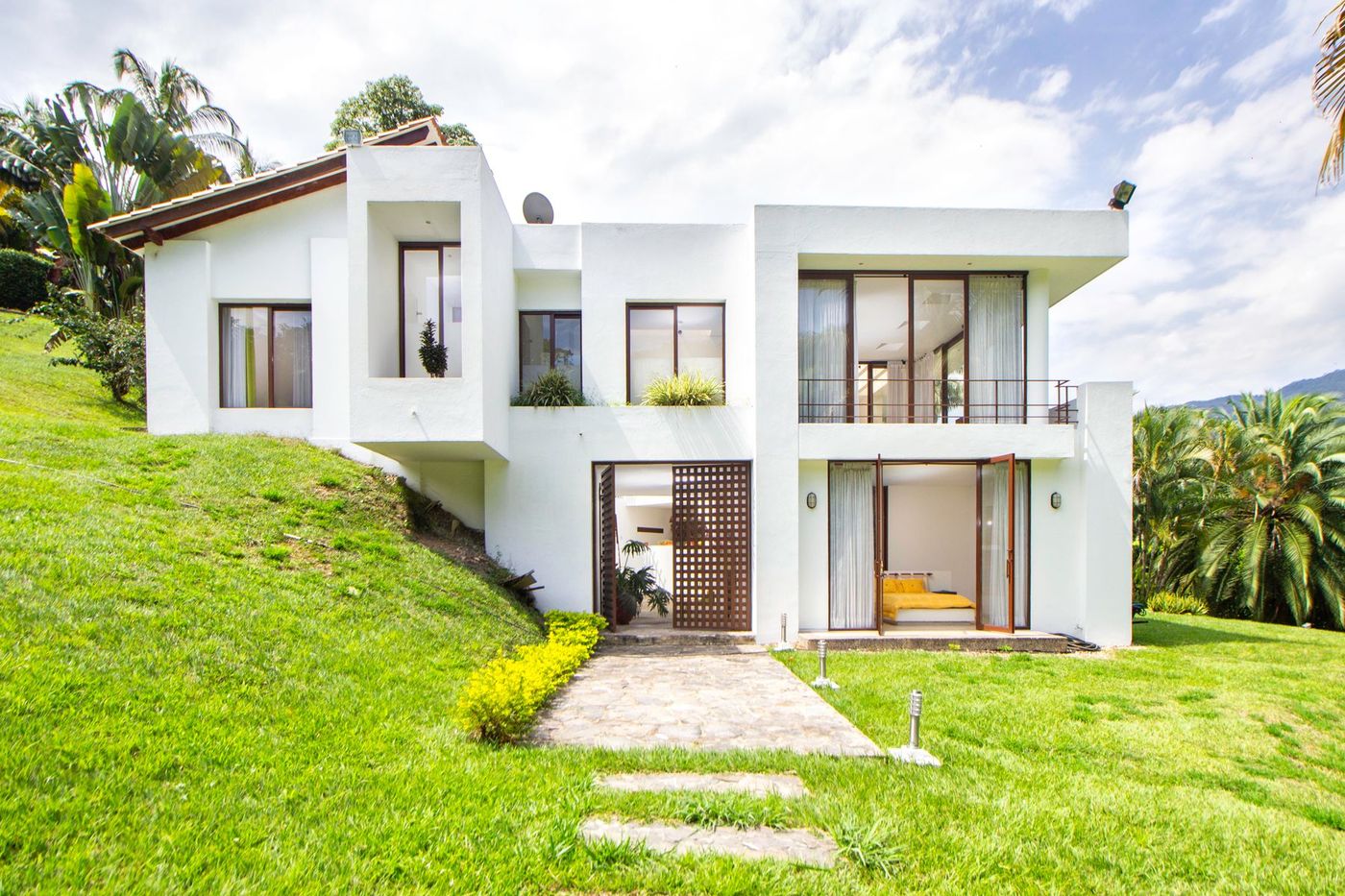 Vivienda blanca de dos plantas con jardín.