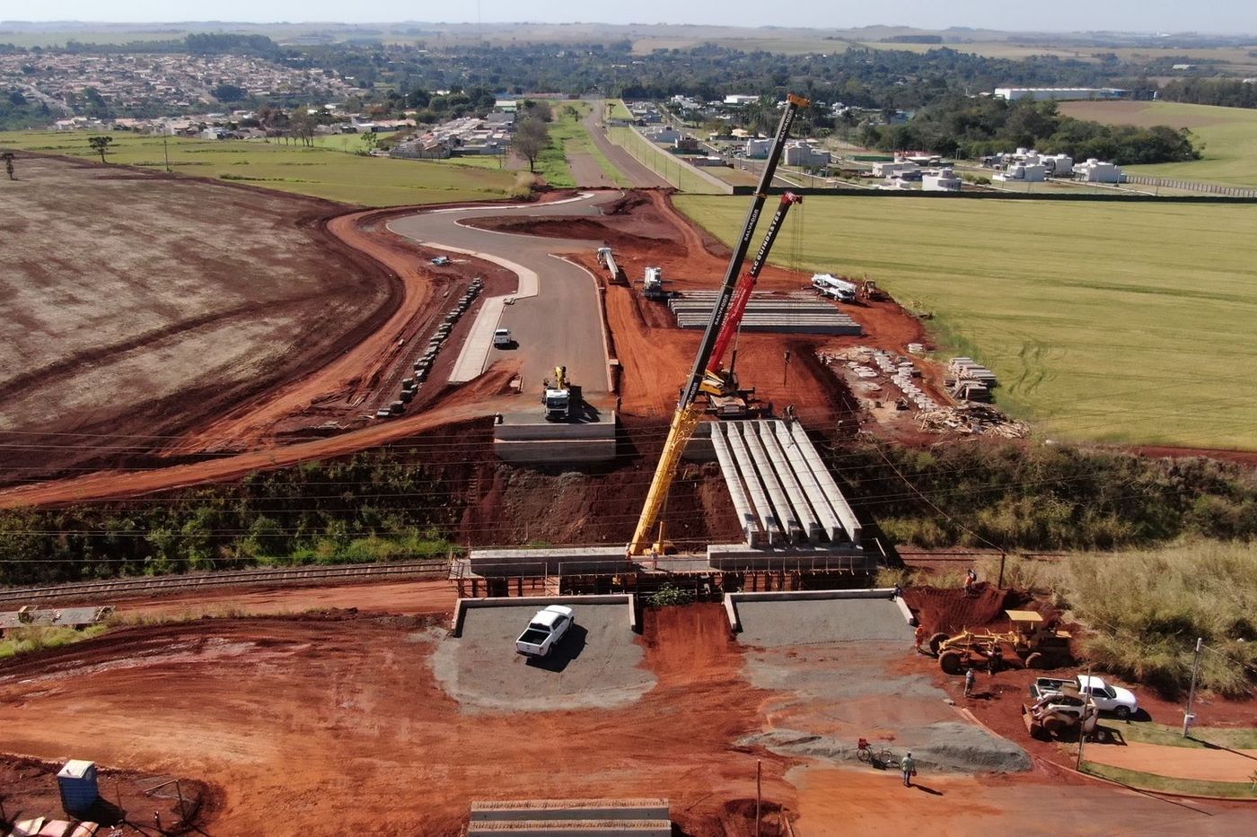 Obra vial con movimiento de tierras y grúa, vista aérea.